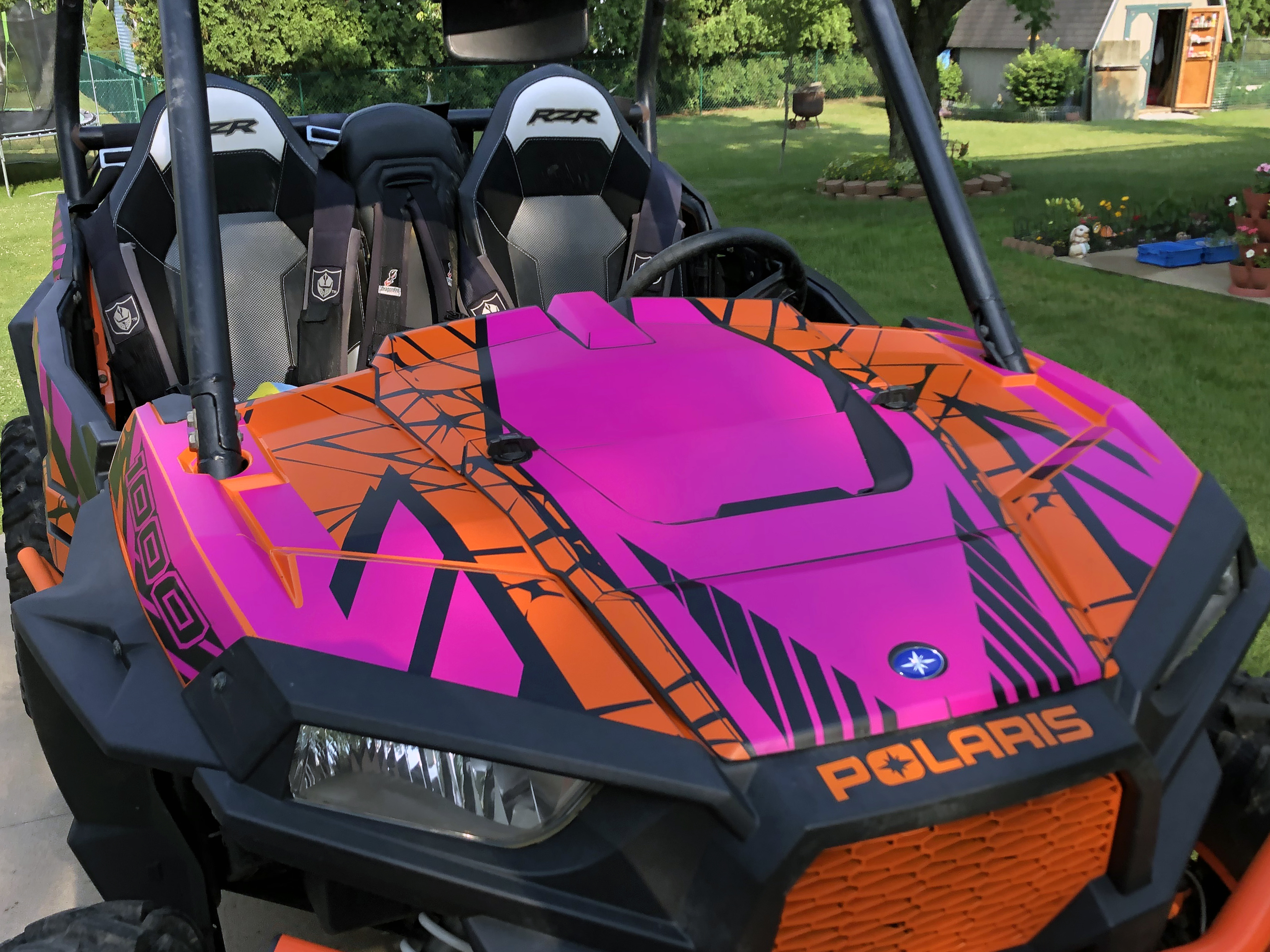 A Polaris RZR XP 2 Door side-by-side with a orange, pink, and black Fractal custom vinyl wrap.