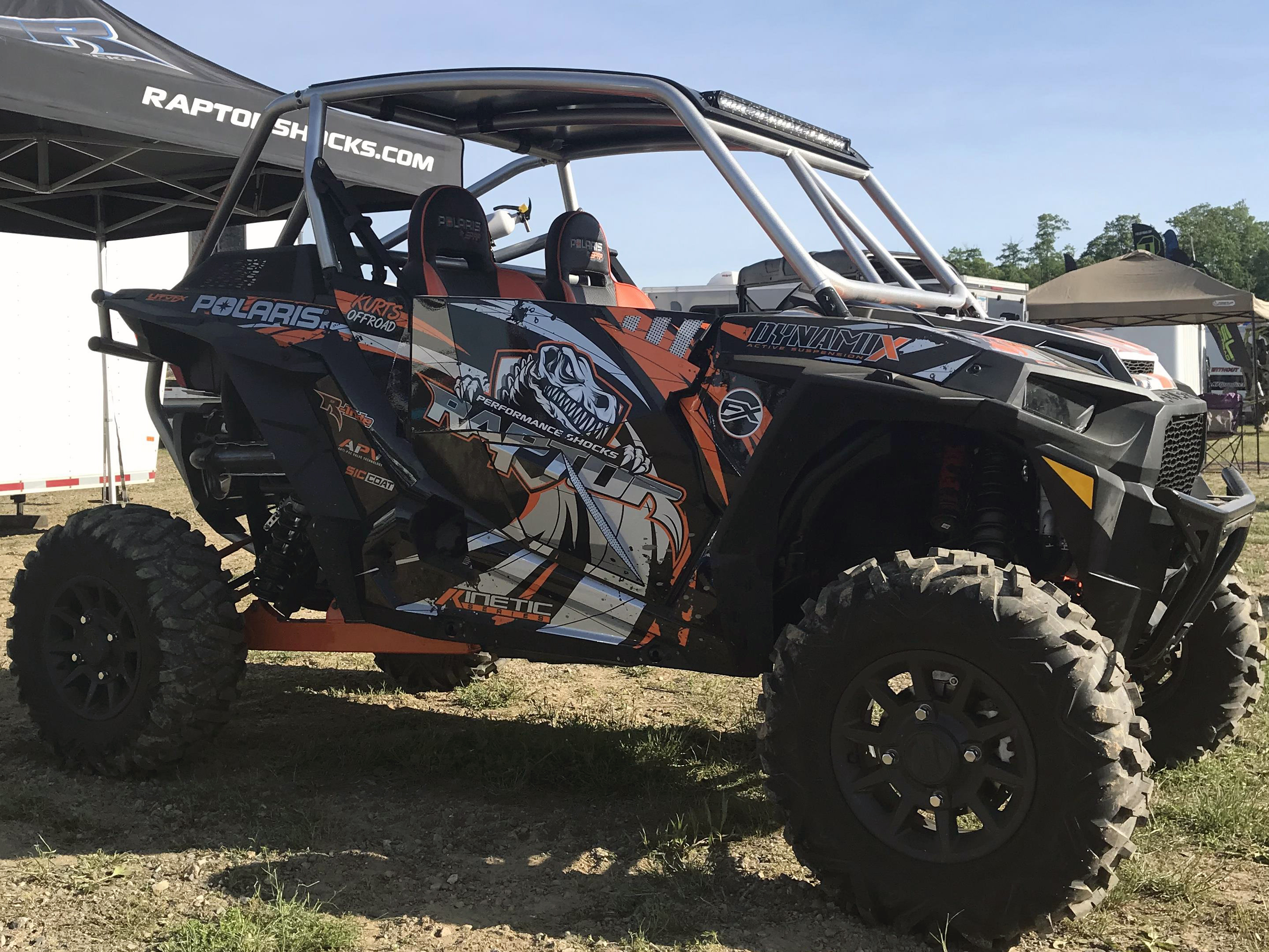 A Polaris RZR XP 2 Door side-by-side with a orange, black, and gray grunge swirl Surge custom vinyl wrap.