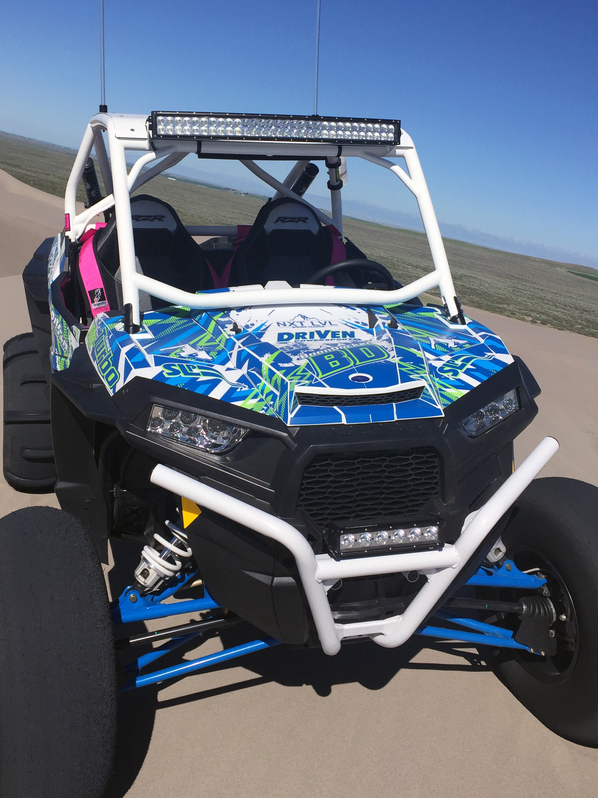 A Polaris RZR XP 2 Door side-by-side with a blue, green, and white lightning design Voltage custom vinyl wrap.