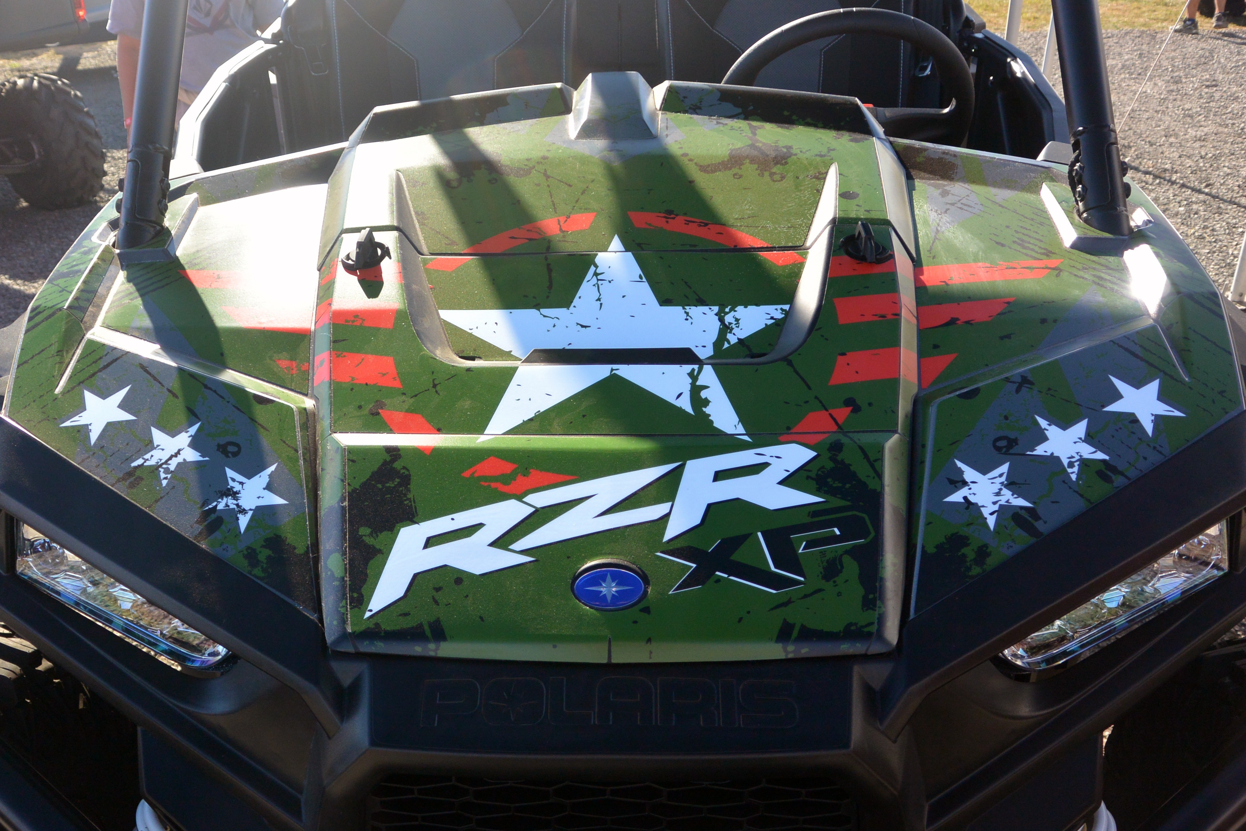 A Polaris RZR XP 2 Door side-by-side with a army green, red, and black grunge Wartorn custom vinyl wrap.