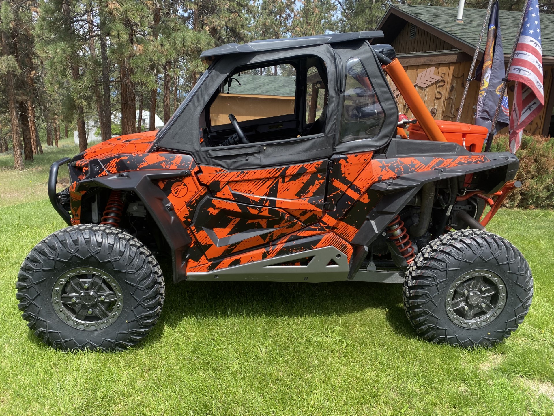 A Polaris RZR XP 2 Door side-by-side with a orange and black grunge Wartorn custom vinyl wrap.