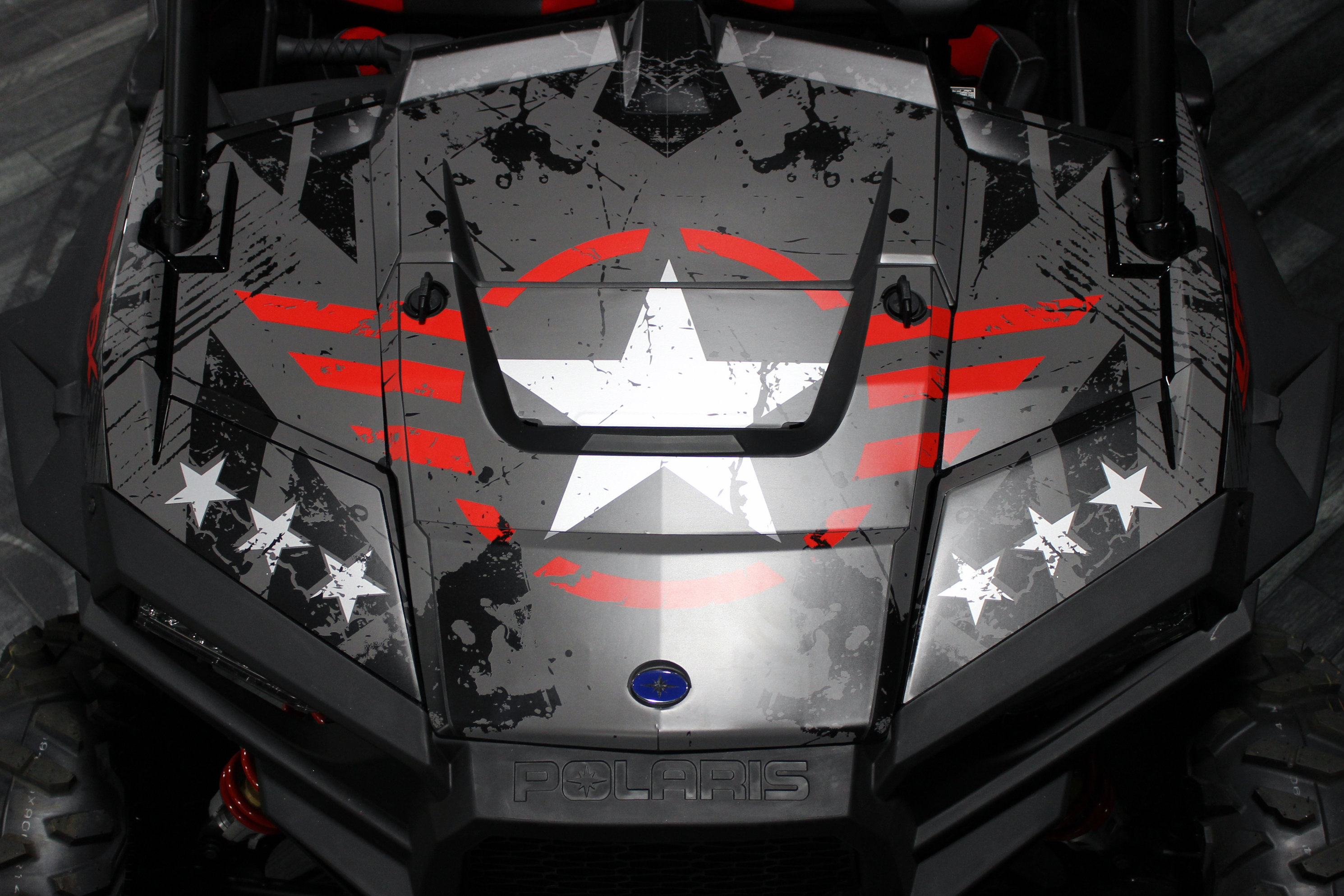 A Polaris RZR XP 2 Door side-by-side with a gray, red, and black grunge Wartorn custom vinyl wrap.