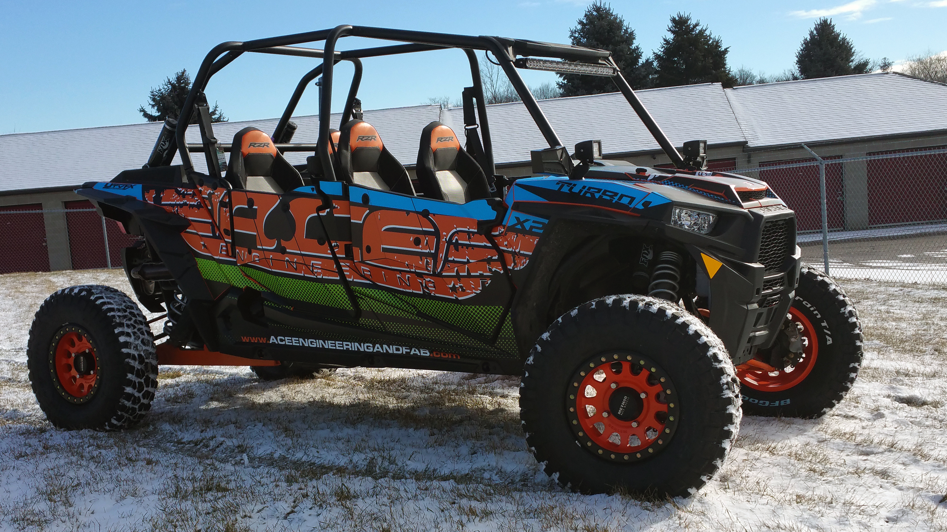 A Polaris RZR XP 4 Door side-by-side with a black, blue, green, and orange grunge Ace Engineering custom vinyl wrap.