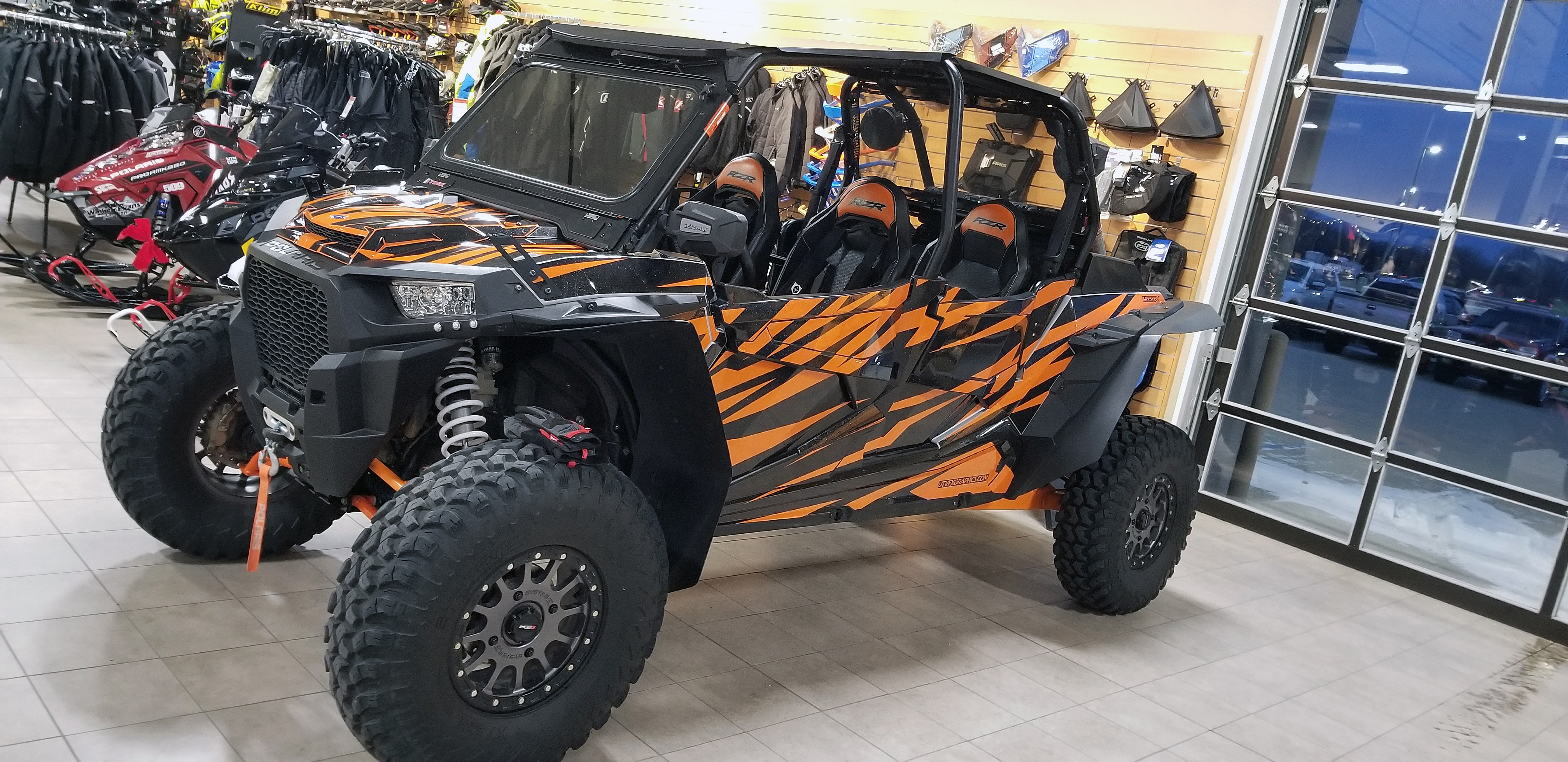 A Polaris RZR XP 4 Door side-by-side with a black and orange stripes Evolution custom vinyl wrap.