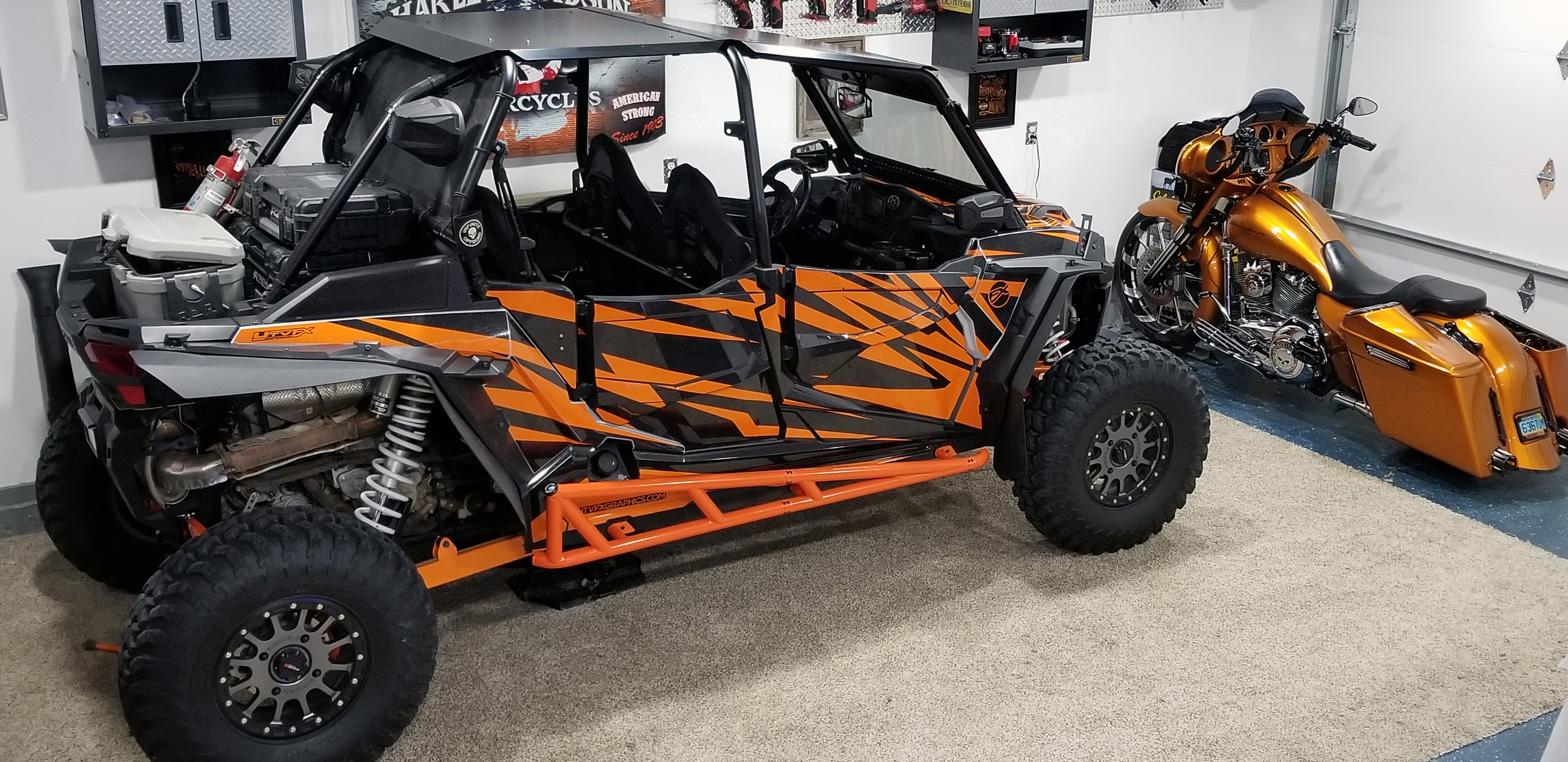 A Polaris RZR XP 4 Door side-by-side with a black and orange stripes Evolution custom vinyl wrap.