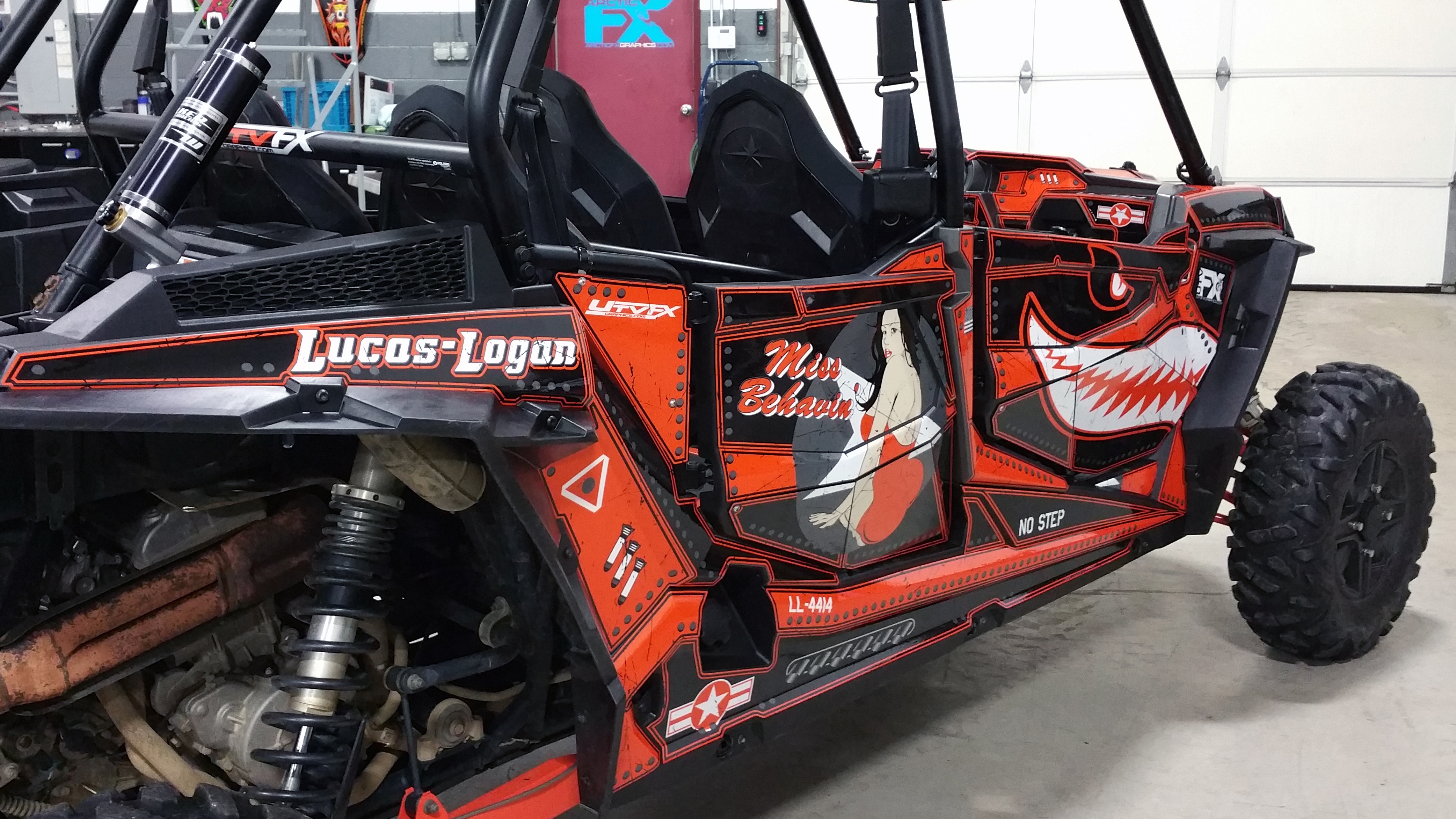 A Polaris RZR XP 4 Door side-by-side with a black, white, and orange flying sharks plane Spitfire custom vinyl wrap.