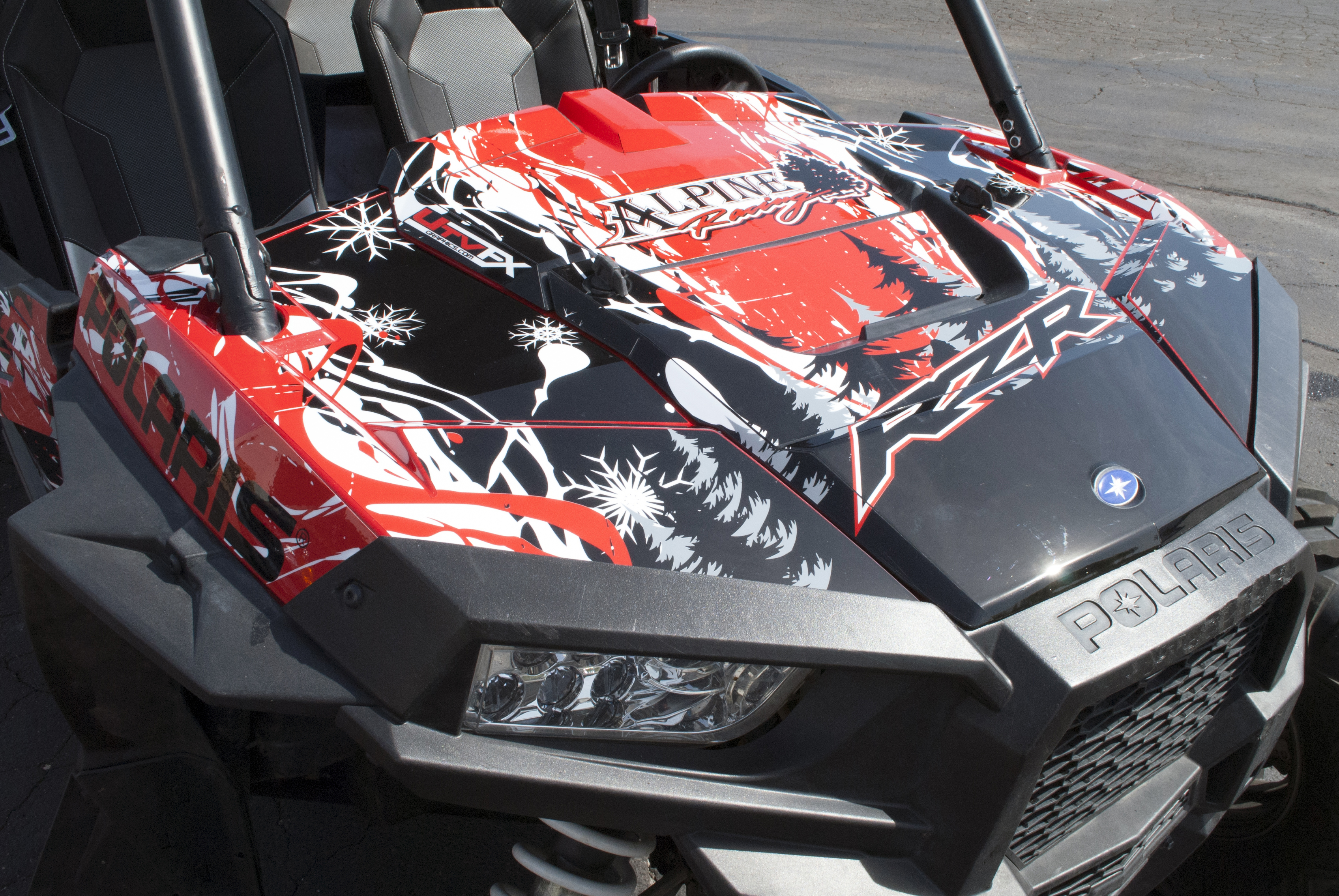 A Polaris RZR XP 4 Door side-by-side with a red, white, and black grunge Sub Zero custom vinyl wrap.