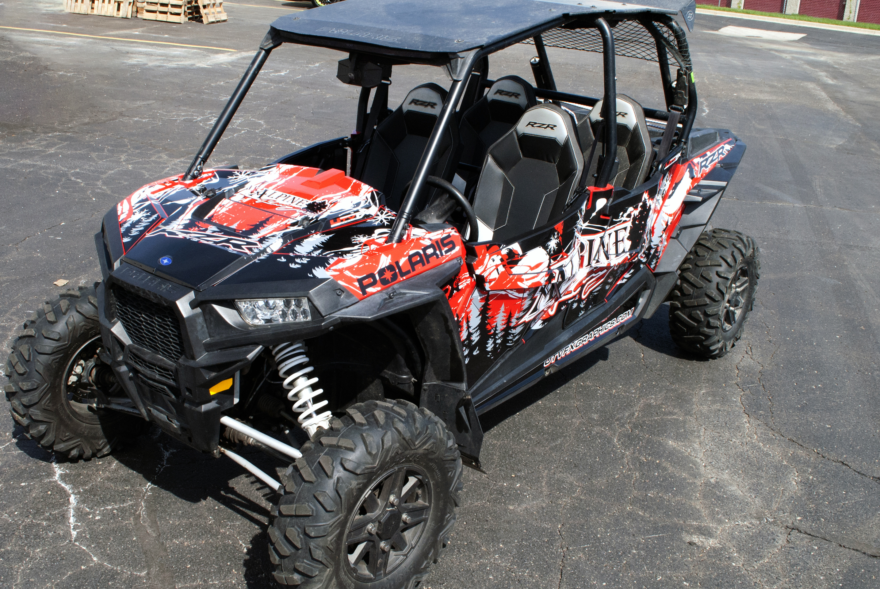 A Polaris RZR XP 4 Door side-by-side with a red, white, and black grunge Sub Zero custom vinyl wrap.