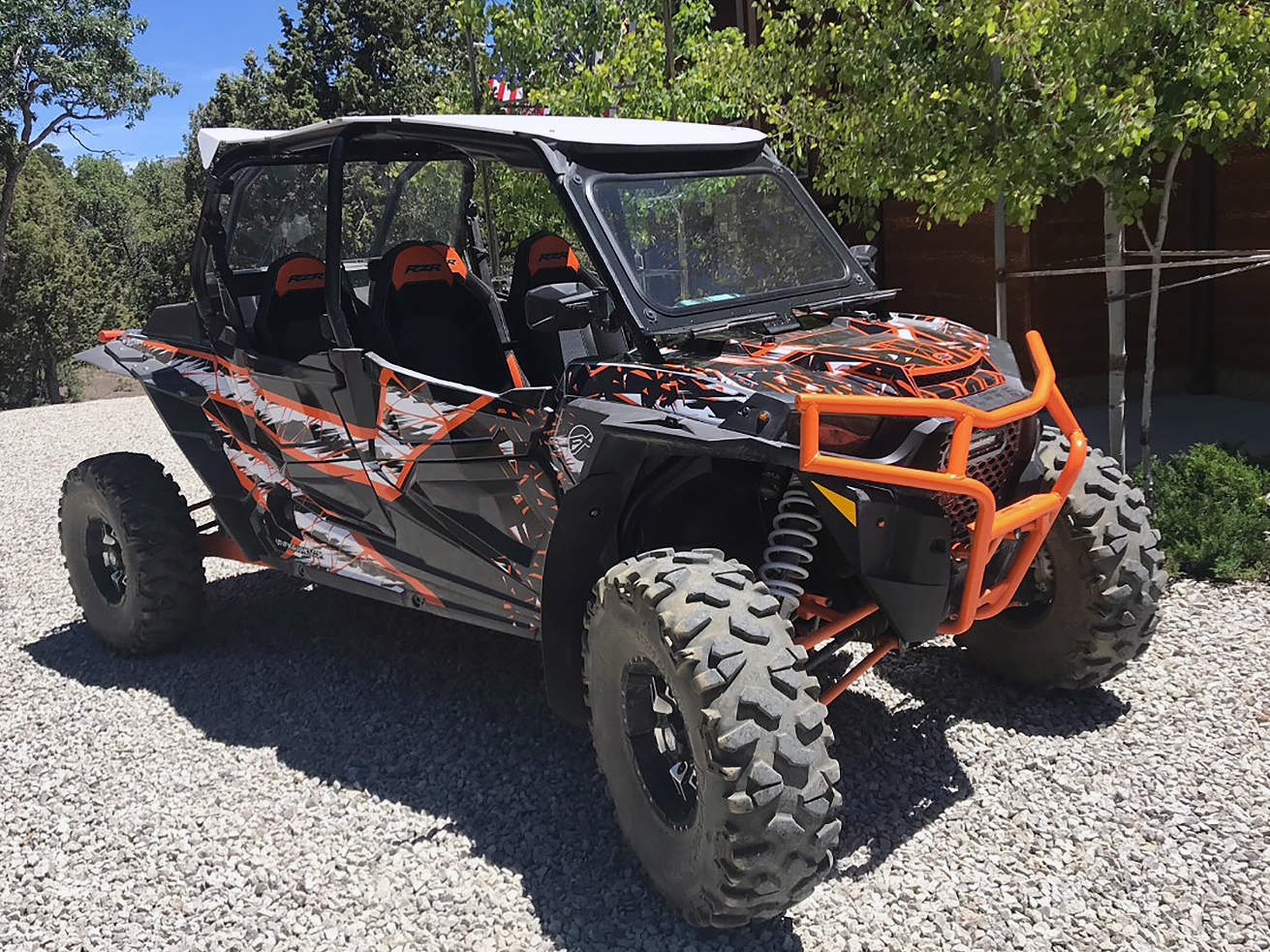A Polaris RZR XP 4 Door side-by-side with a black, white, and orange geometric pattern Virus custom vinyl wrap.
