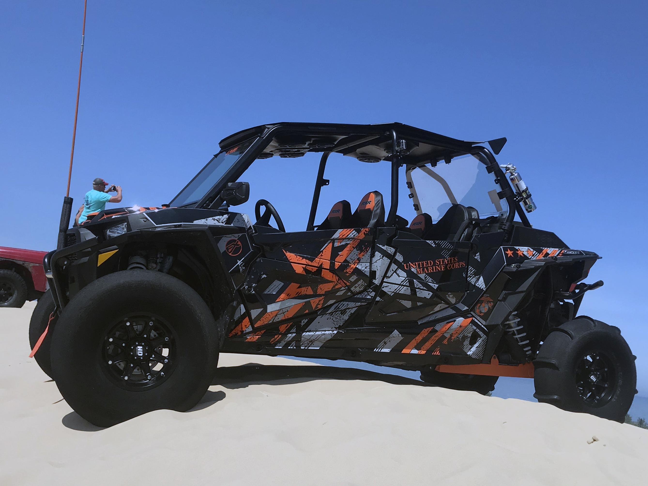 A Polaris RZR XP 4 Door side-by-side with a black, gray, and orange grunge Wartorn custom vinyl wrap.