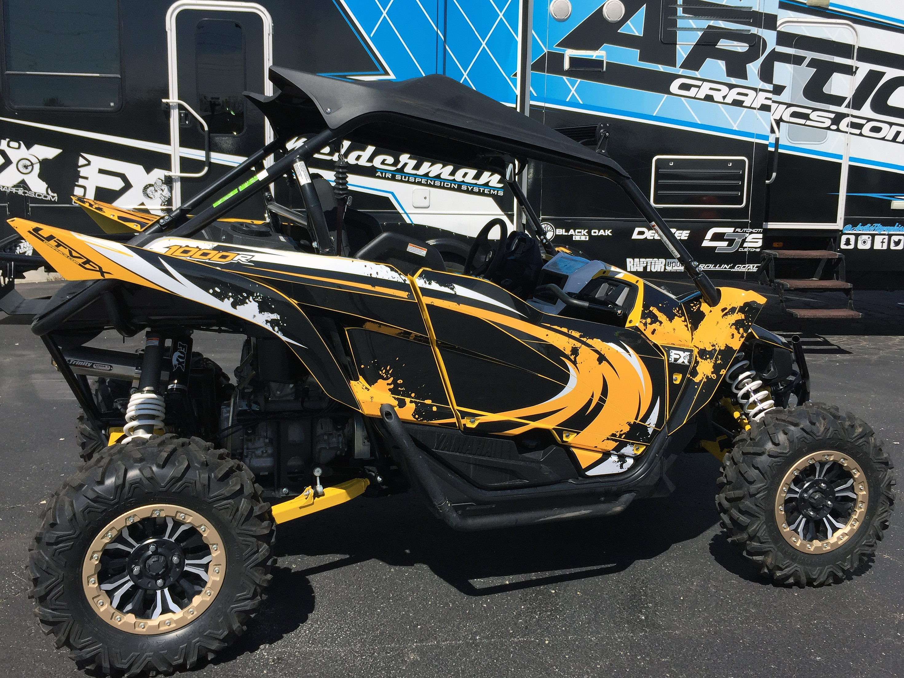 A Yamaha YXZ1000R side-by-side with a yellow, black, and white grunge swirl Surge custom vinyl wrap.