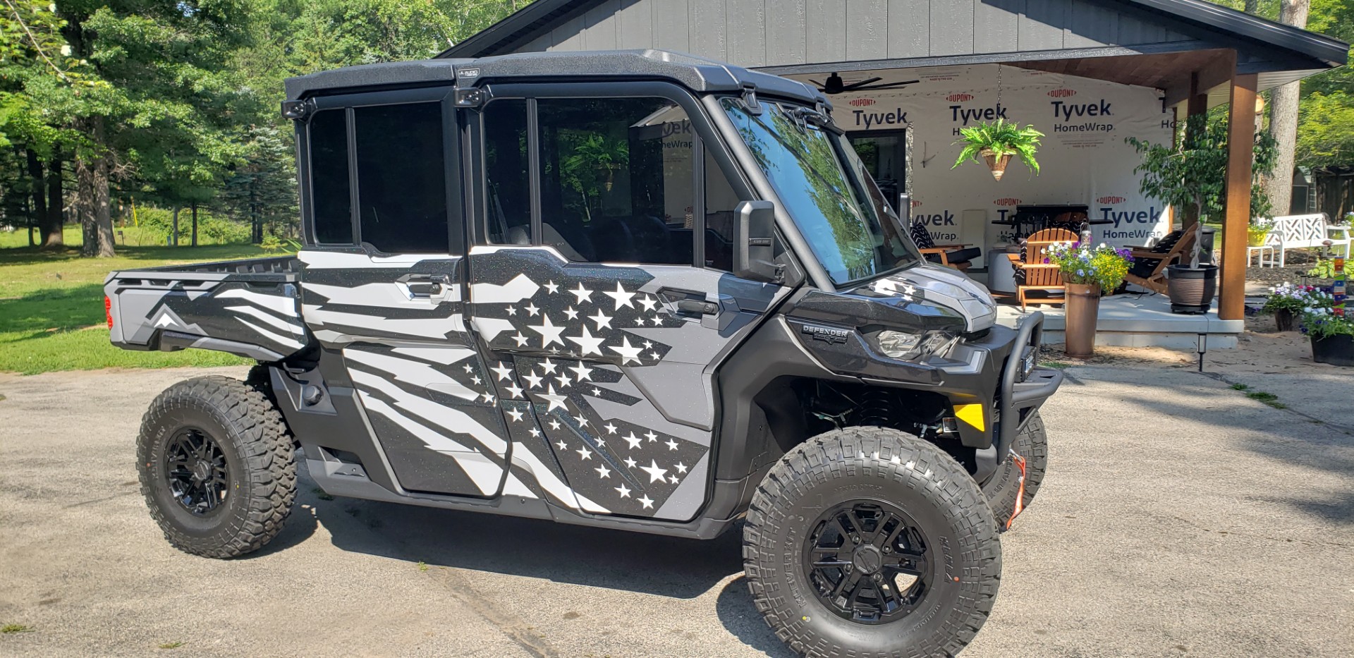 A Can-Am Defender Max with a black, charcoal gray, asphalt gray, and white Lef Alvarasson Merica custom wrap with halo flake laminate.