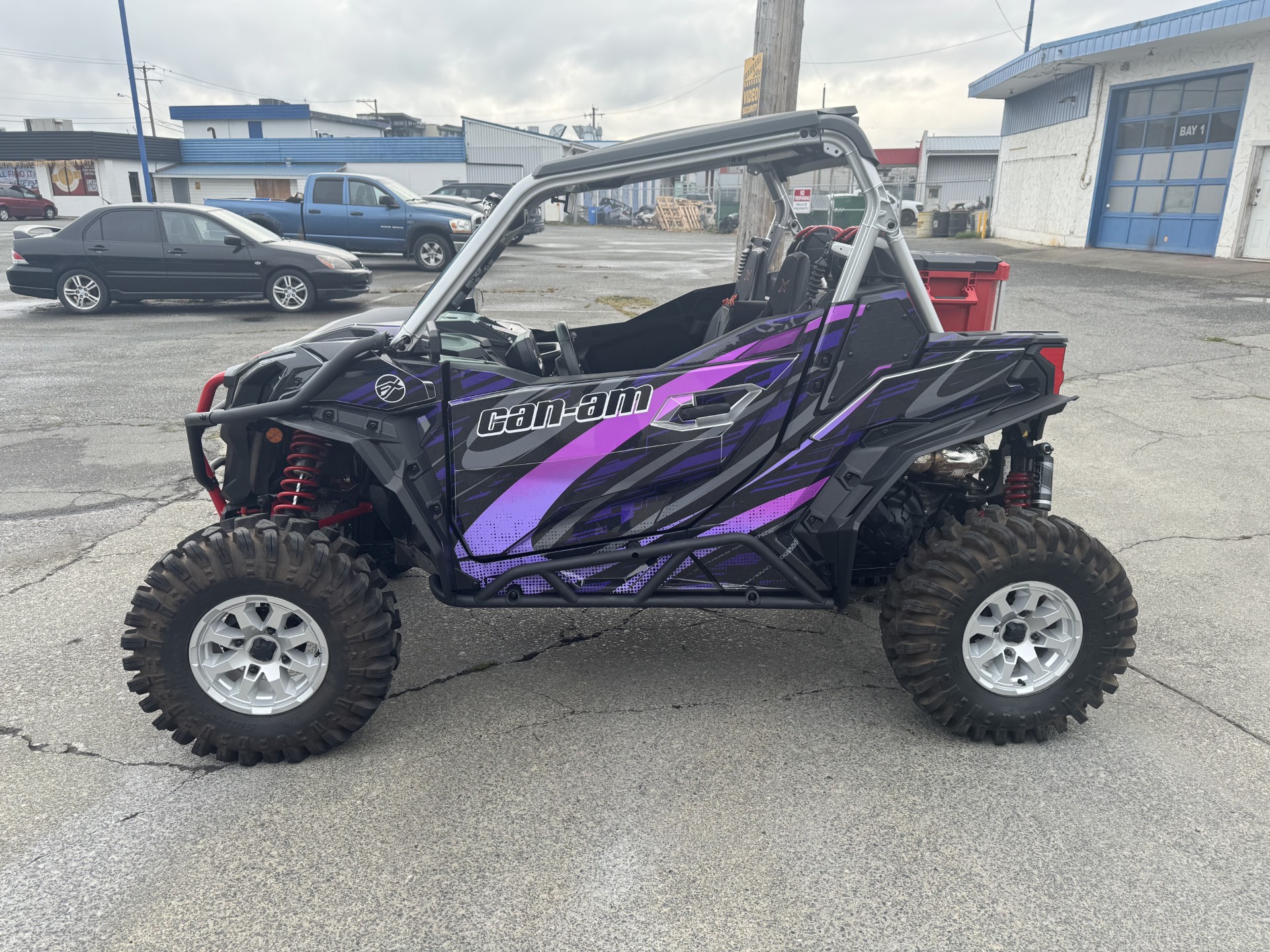 A Can-Am Maverick Sport side-by-side with a black, khaos purple, asphalt gray, lilac purple, and gang purple Electra custom vinyl wrap with silver flake laminate.