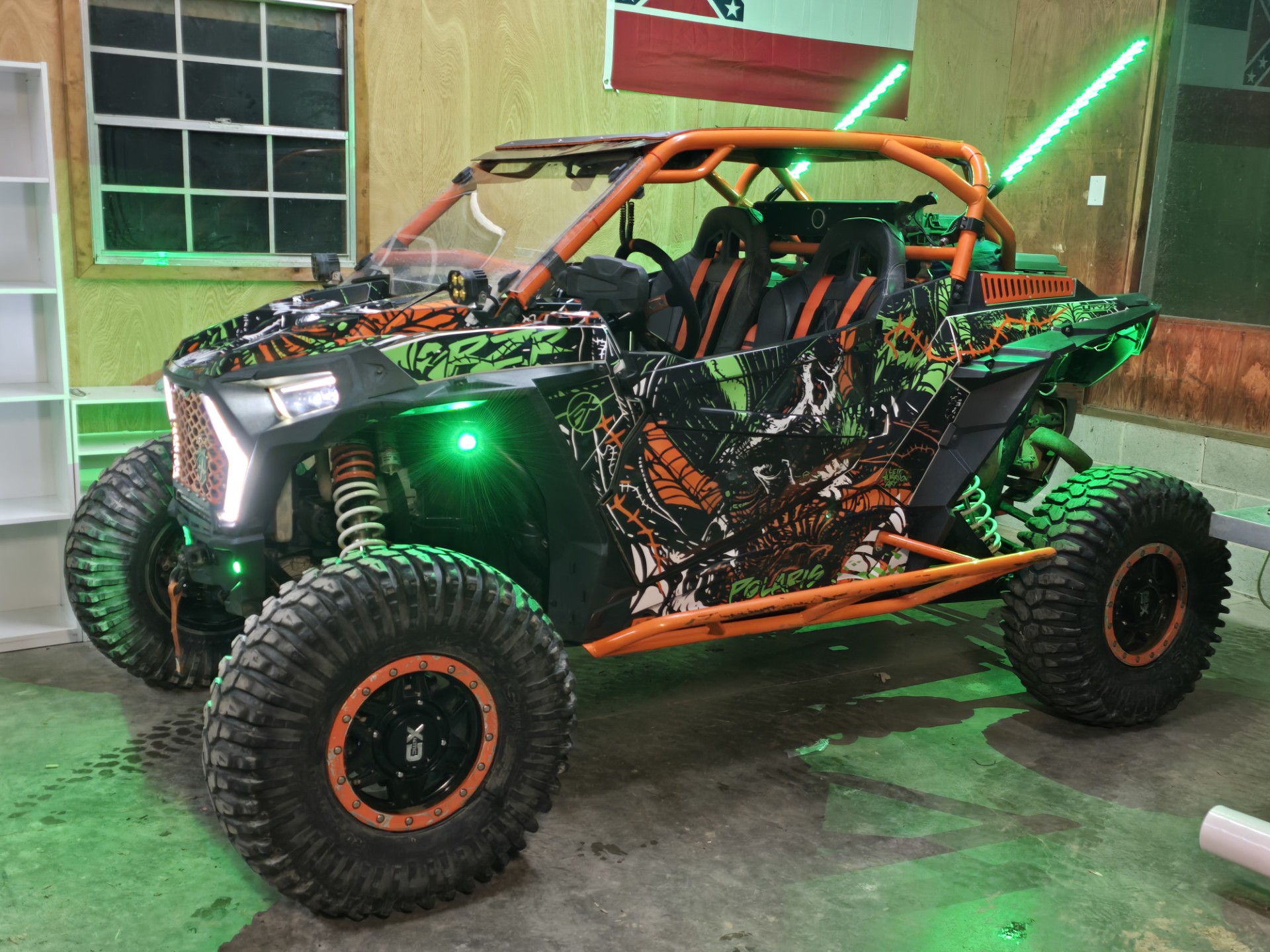 A Polaris RZR XP 2-door 2018+ side-by-side with a gunmetal gray, electric green, orange, and white Leif Alvarasson Wicked custom vinyl wrap.