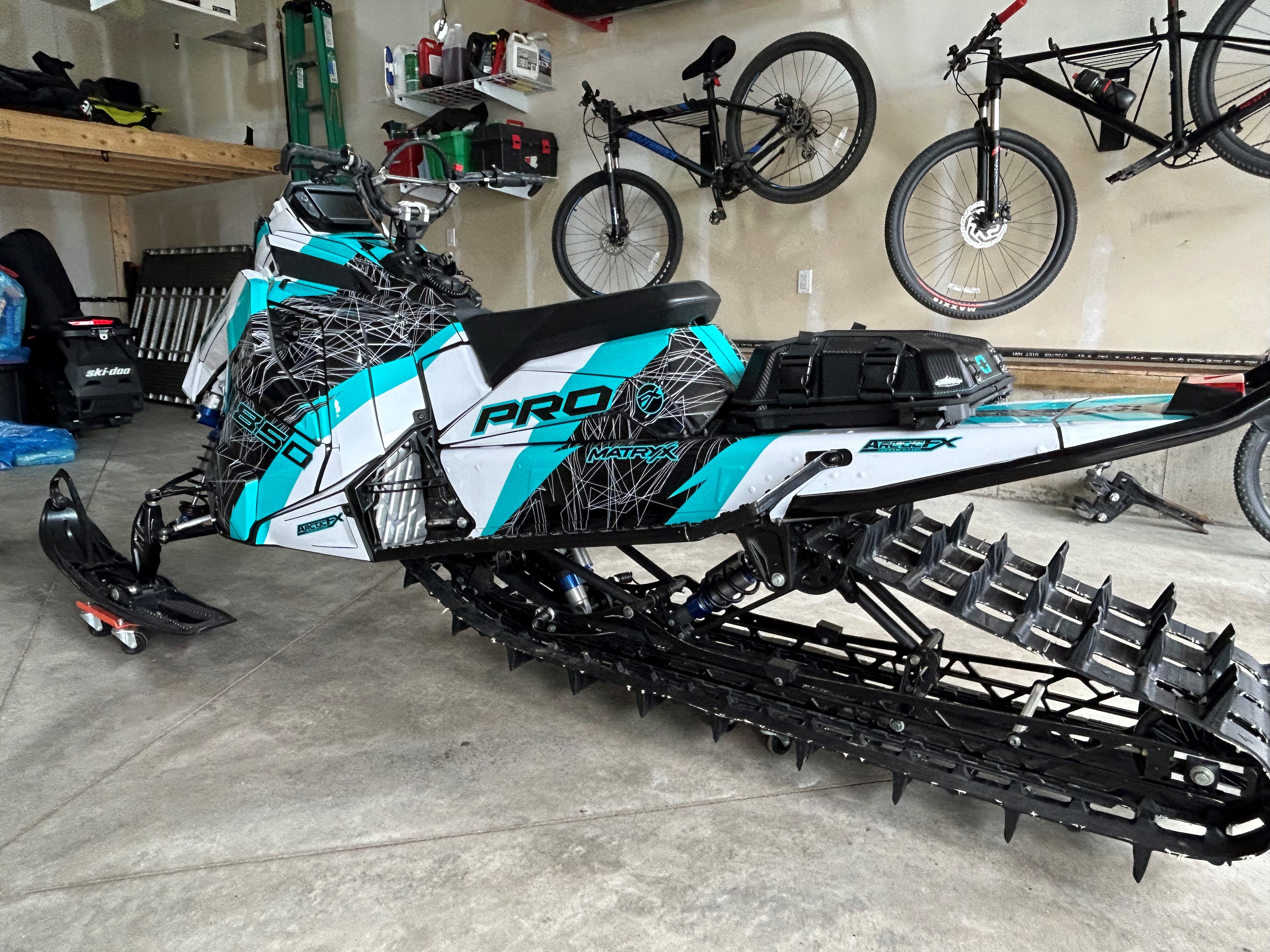 A Polaris Matryx Mountain snowmobile with a black, white, and ice blue Y2K custom vinyl wrap with gloss laminate.